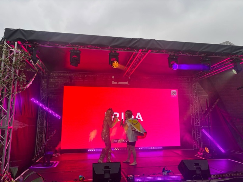 Performers on the Barnsley Pride main stage under pink and red lighting, with the LED wall behind