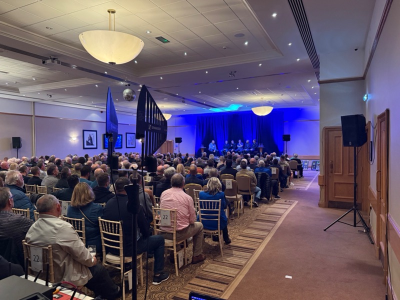 A full room watching a panel of Everton legends on a blue-lit stage at Crowne Plaza Chester