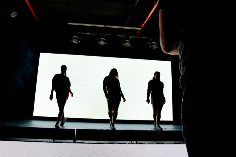 Example image: models silhouetted on the catwalk against a bright stage screen