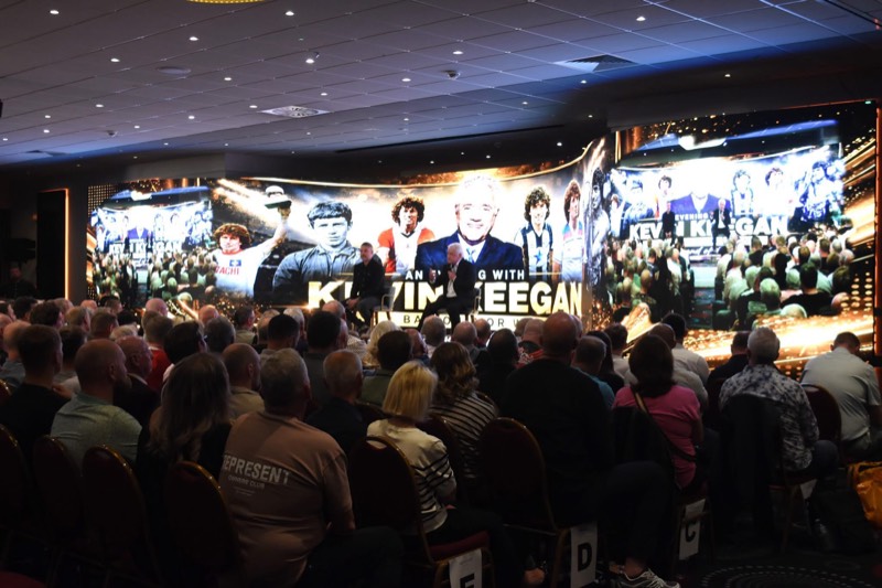 Audience in front of a curved LED wall at a live speaker event