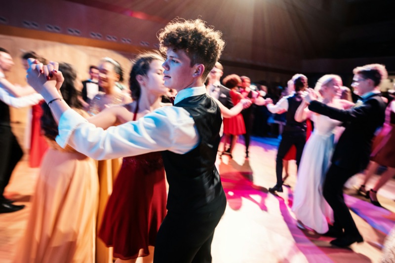 Example image: students in suits and prom dresses dancing under coloured lights