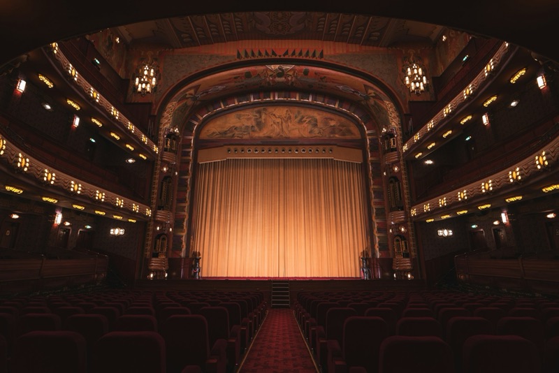 Traditional theatre auditorium with red seats and a gold curtain
