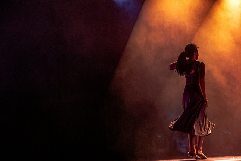Dancer in a warm shaft of stage light and haze